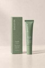 A matte sage green cosmetic box and matching squeeze tube of MATINÉ Vanilla Lip Balm, set against a warm beige background.